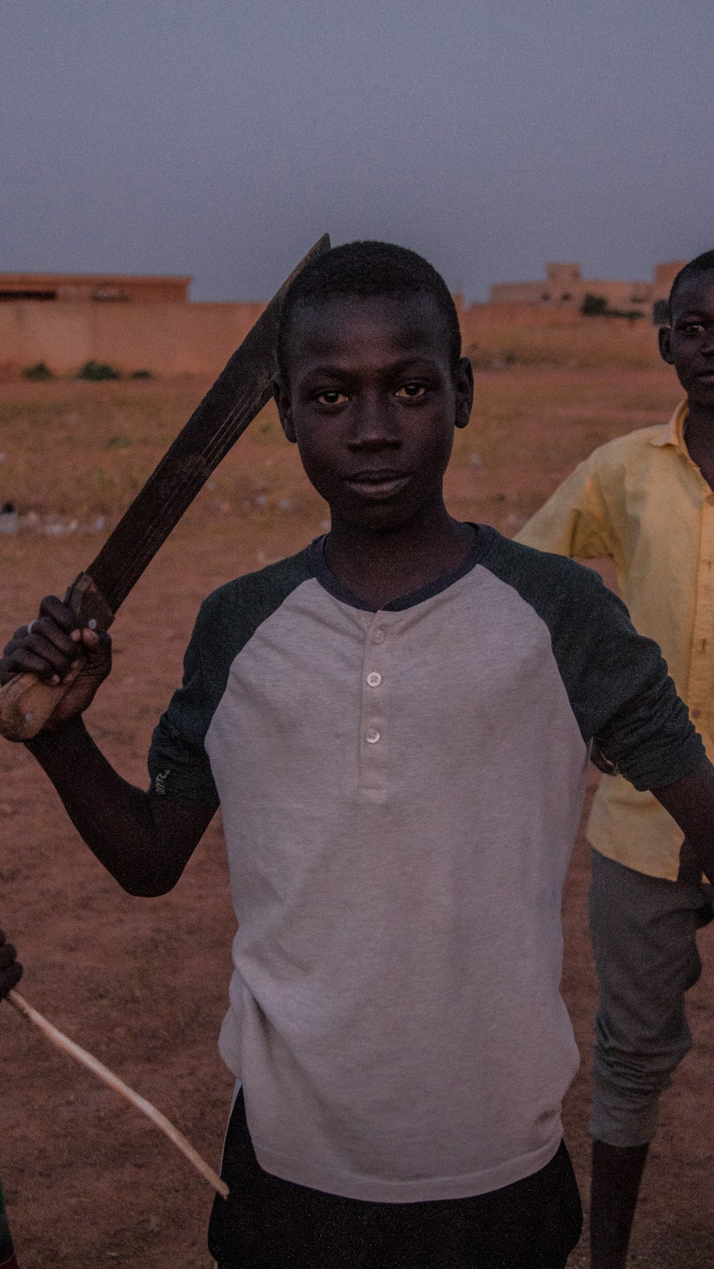 boy in white and black long sleeve shirt holding brown wooden stick