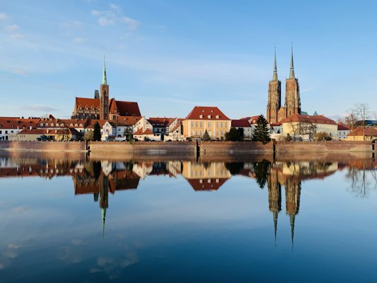 Brown and white concrete building near body of water during daytime — Wrocław, Poland