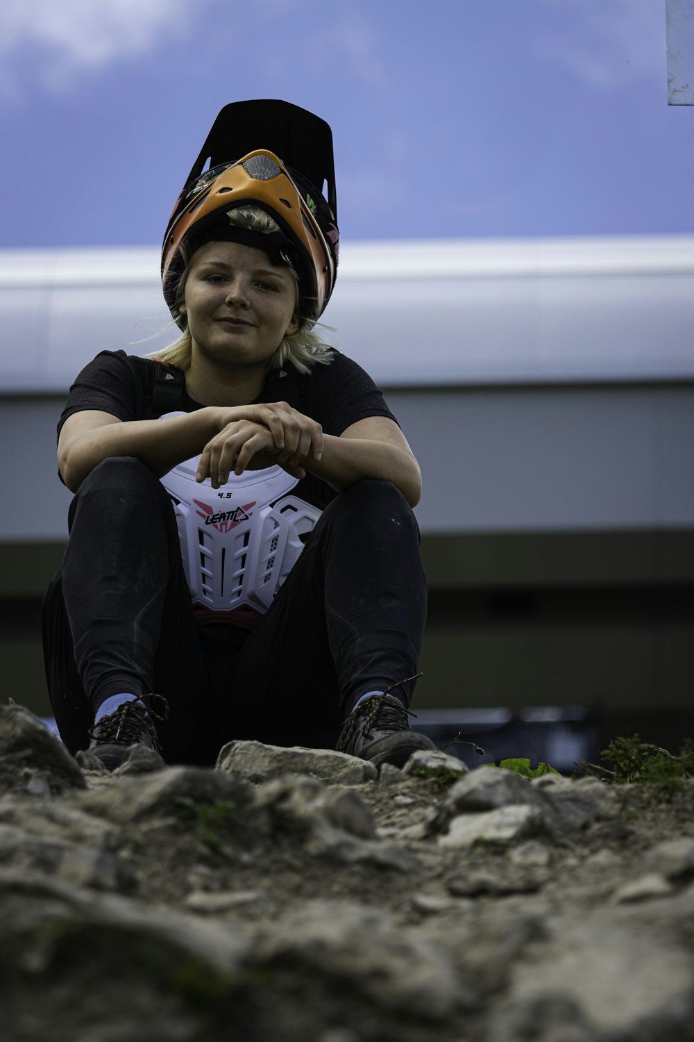 boy in black t-shirt and helmet sitting on rock during daytime