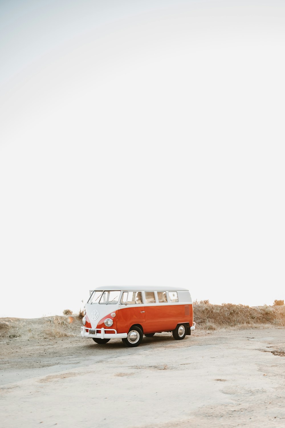 Volkswagen T-1 rojo y blanco sobre arena marrón durante el día