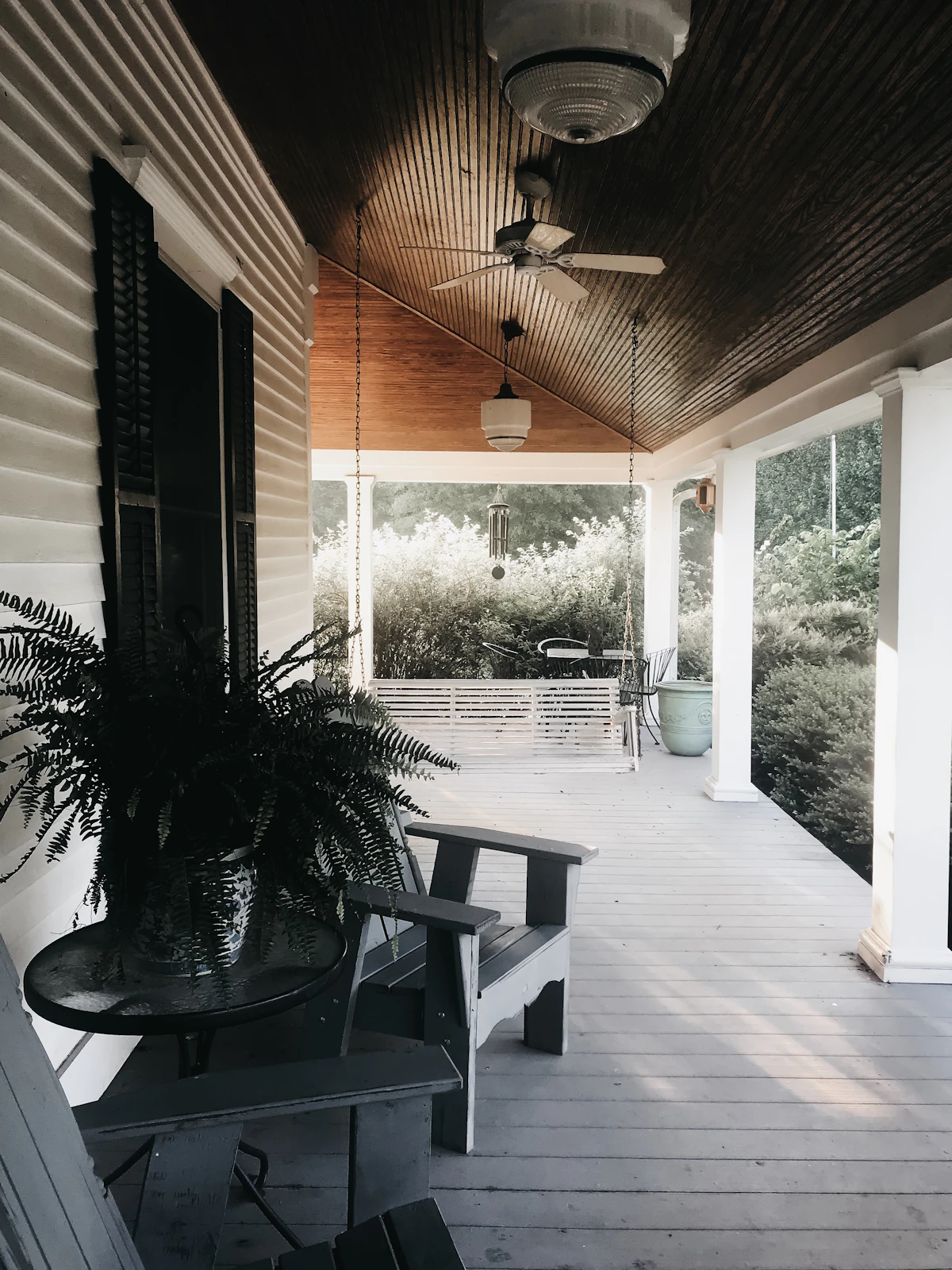 A white front porch with rocking chairs and a ceiling fan