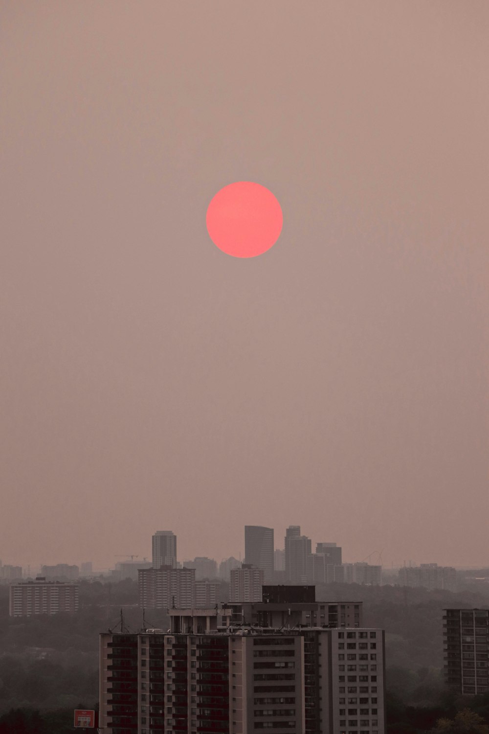 skyline della città durante il tramonto con la luna rossa