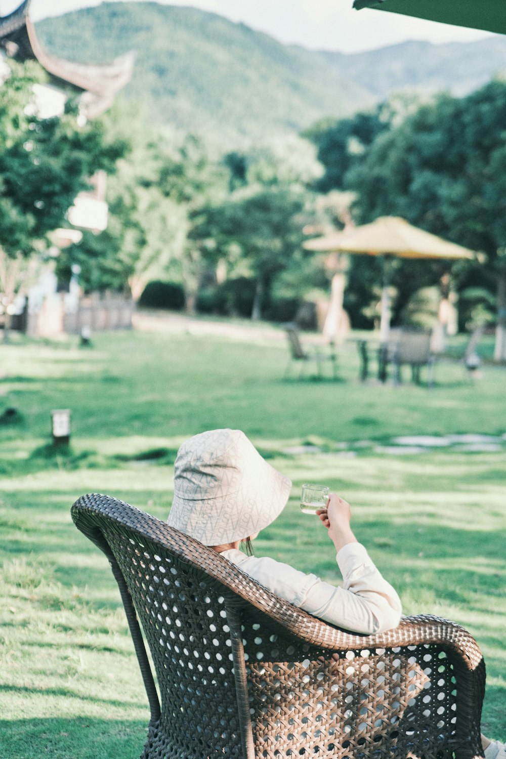 woman in white long sleeve shirt and brown sun hat sitting on green grass field during
