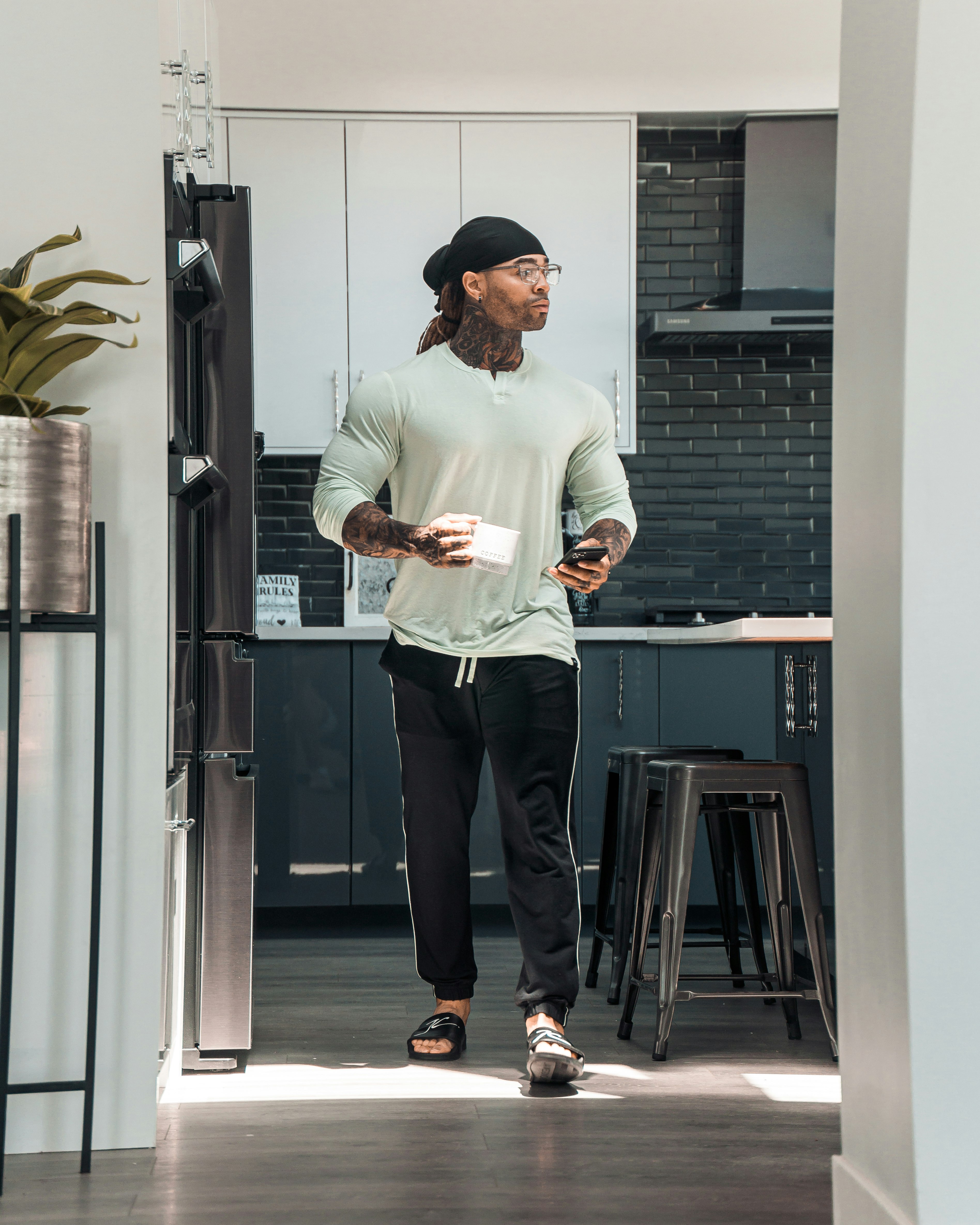 man in white crew neck t-shirt and black pants standing beside black wooden door