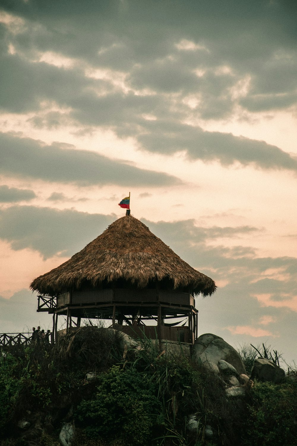 brown nipa hut on green grass field under cloudy sky during daytime