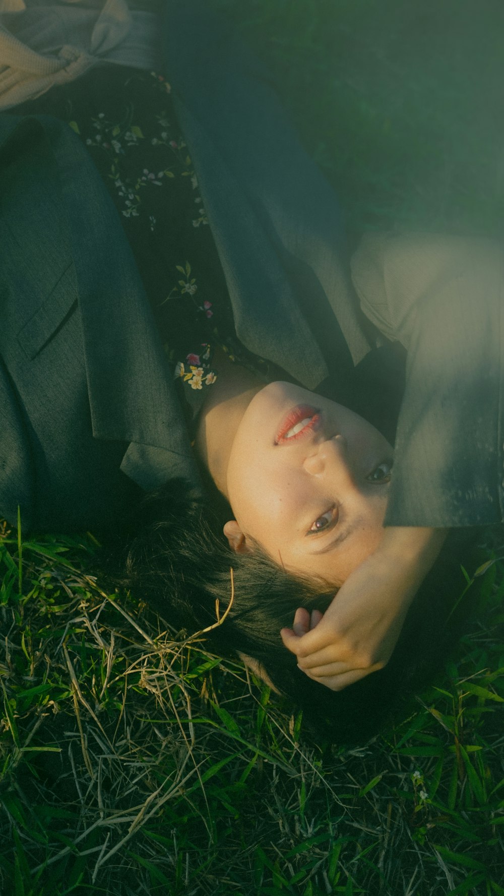 woman in black blazer lying on green grass