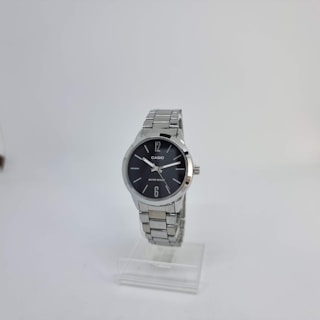 A silver wristwatch with a round black dial is displayed on a clear stand. The dial has a minimalist design with silver hour markers at 12 and 6, and two simple silver hands. The watch displays the brand name and water resistance feature on the dial.