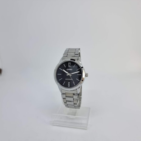 A silver wristwatch with a round black dial is displayed on a clear stand. The dial has a minimalist design with silver hour markers at 12 and 6, and two simple silver hands. The watch displays the brand name and water resistance feature on the dial.