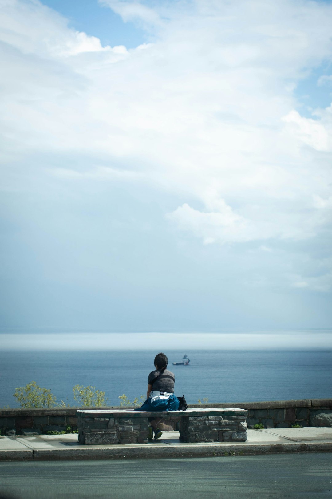 man in black jacket sitting on brown wooden dock during daytime