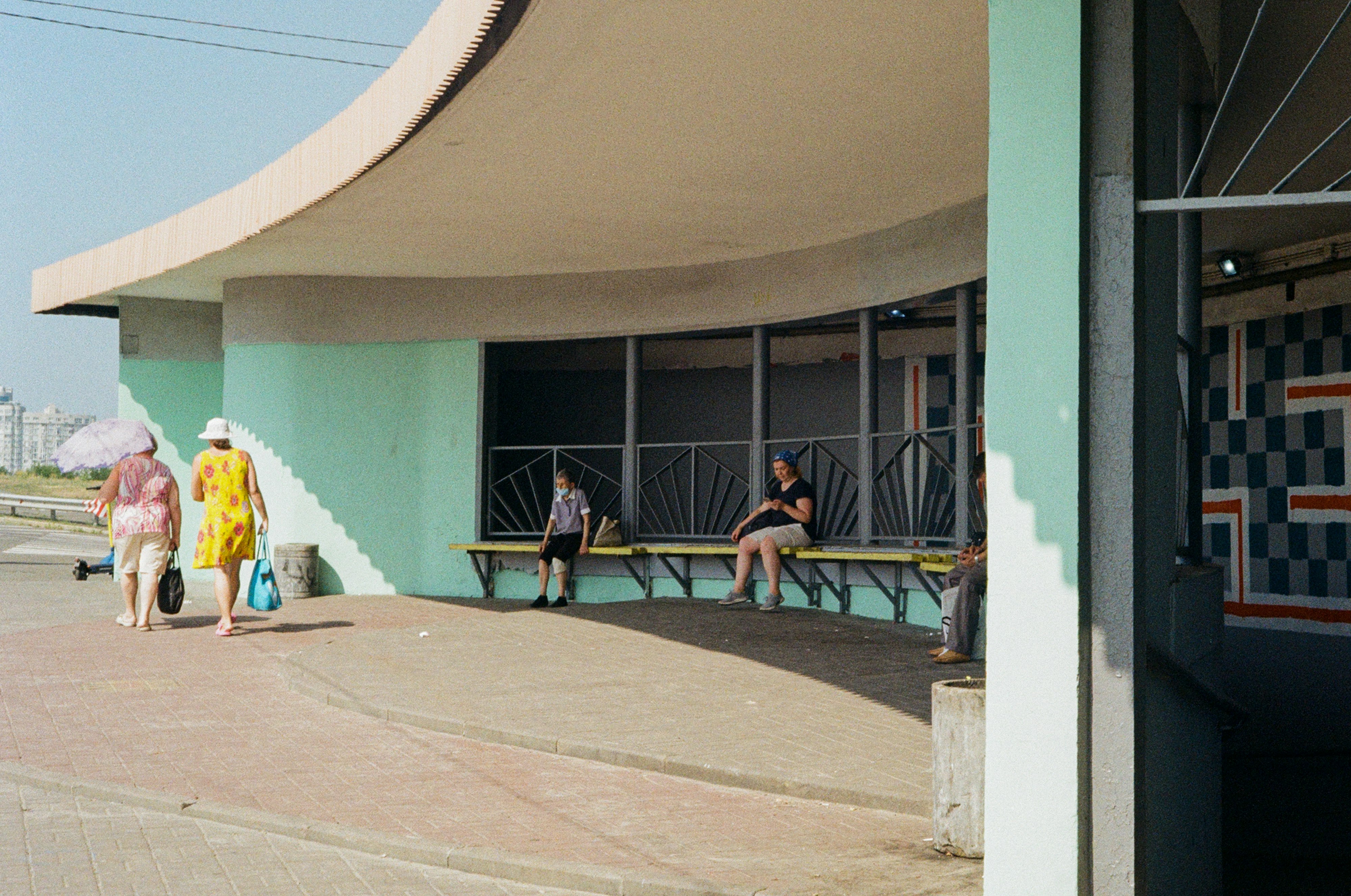 2 women sitting on bench near wall