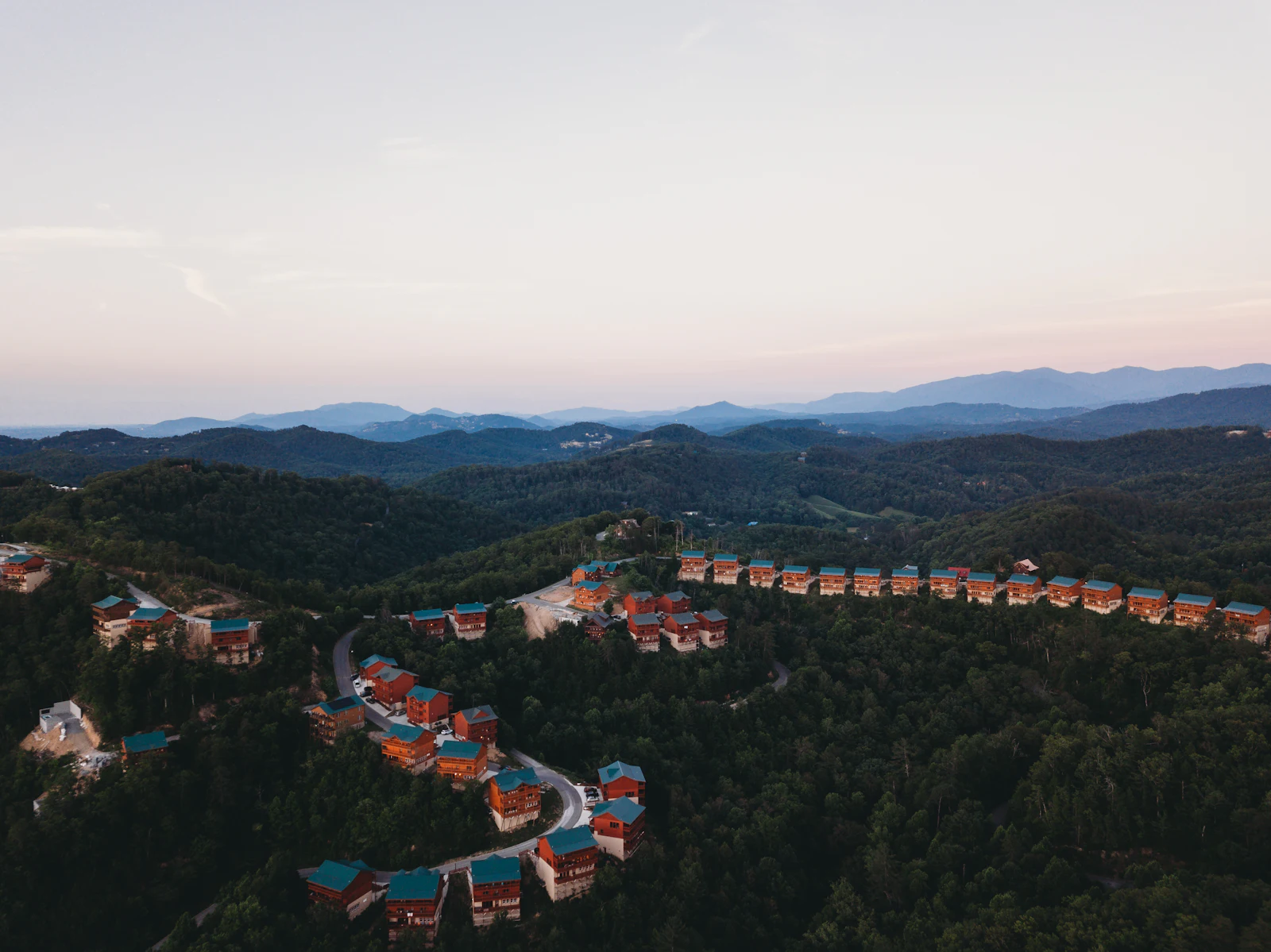 An aerial view of buildings below wooded mountains.