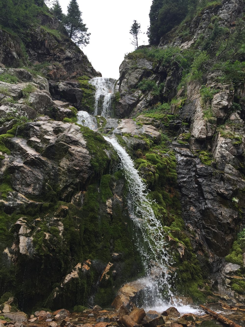 water falls between rocky mountain during daytime