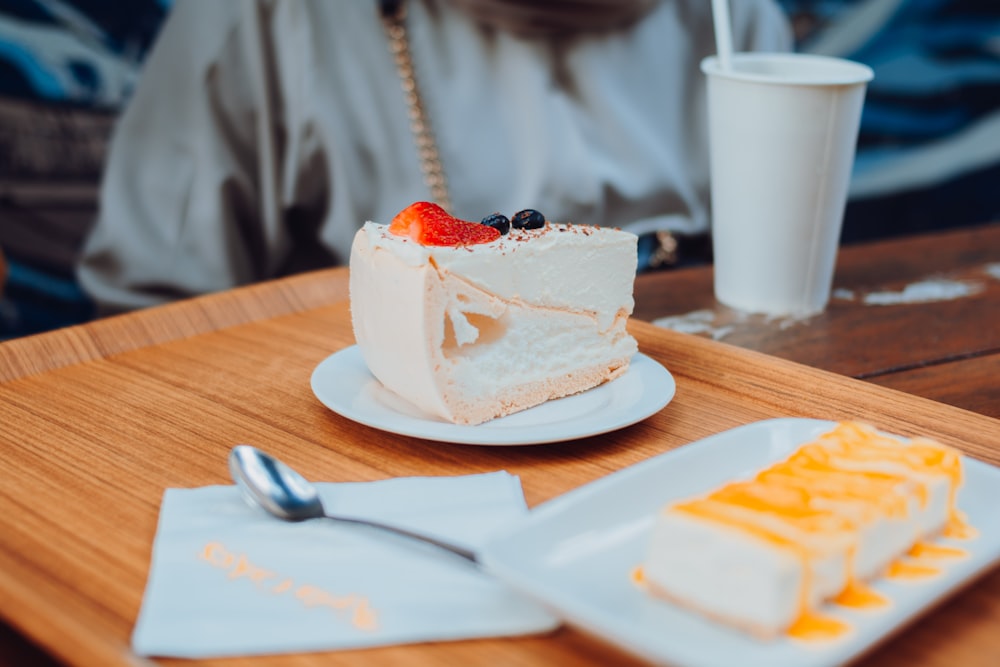 white cake on white ceramic plate beside silver spoon and white ceramic mug on brown wooden