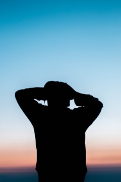 Sunset silhouette of a person enjoying music with headphones