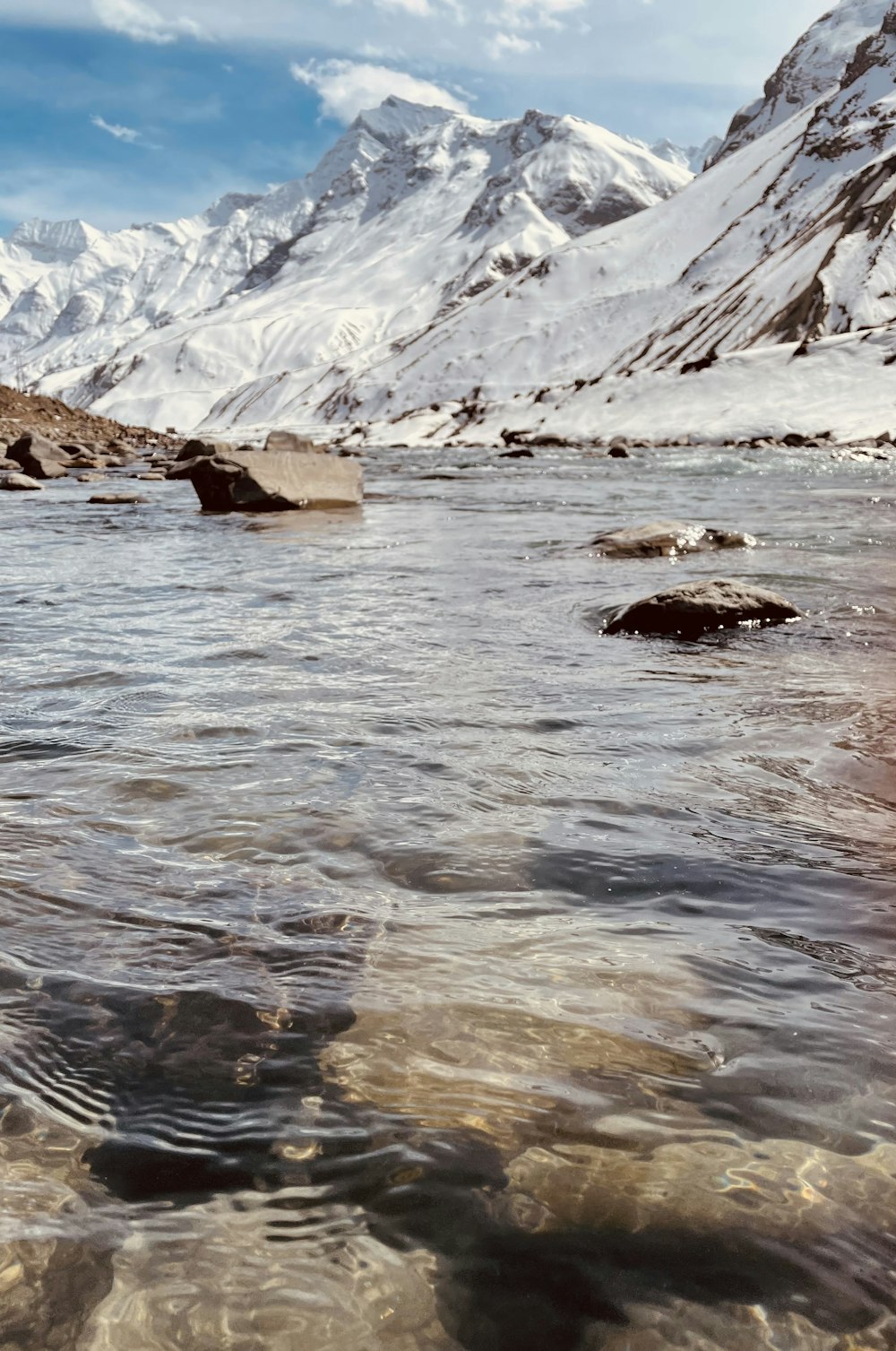 brown rock on river near snow covered mountain during daytime