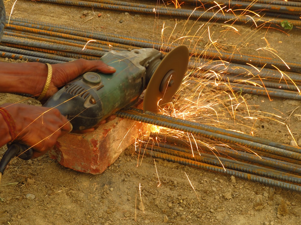 person holding green and brown metal tool