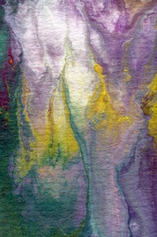 A vibrant, abstract watercolor painting featuring flowing patterns of purple, yellow, green, and cream hues. The colors blend seamlessly in a marbled effect, creating an impression of movement and fluidity.
