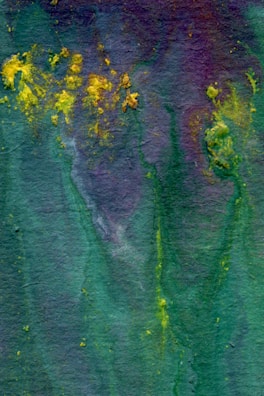 An abstract watercolor painting features a blend of deep green, purple, and scattered bursts of bright yellow. The textured background creates a fluid and organic appearance, with colors merging seamlessly.