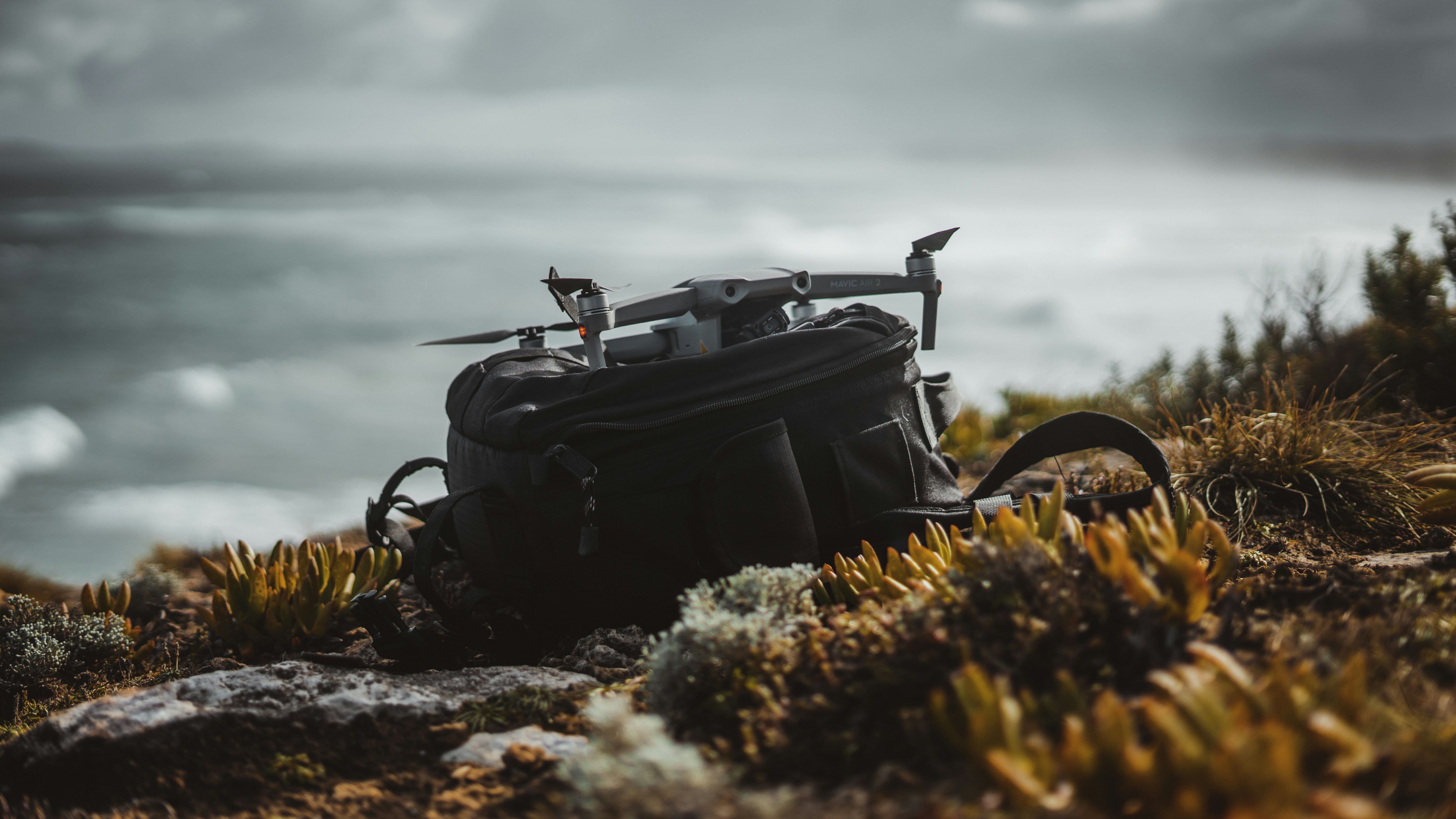 black leather backpack on rocky shore during daytime, 