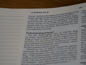 A close-up view of an open page from a book, specifically from the Bible, displaying text in English. The visible section includes passages from 2 Kings 15:6, discussing kings Jotham and Zechariah. The text is printed in a serif font, with chapter numbers and headings in bold.