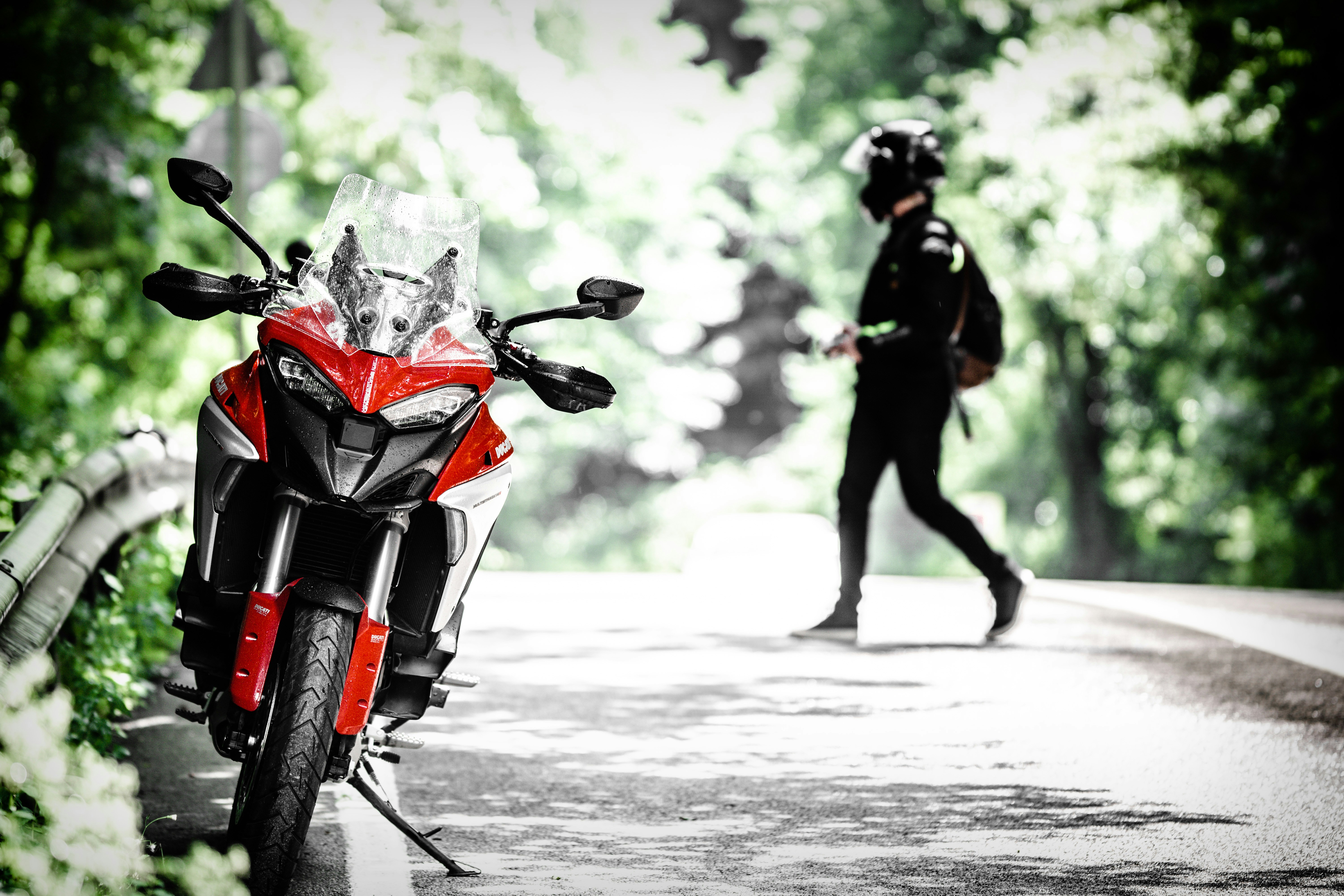 man in black jacket riding red and white motorcycle