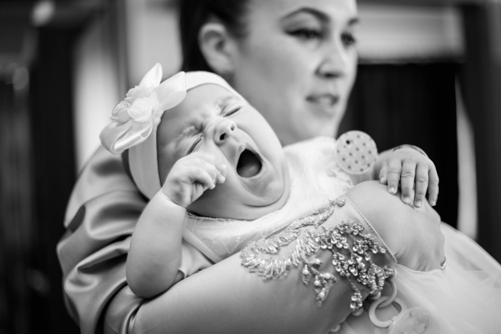 man in gray shirt carrying baby in grayscale photography