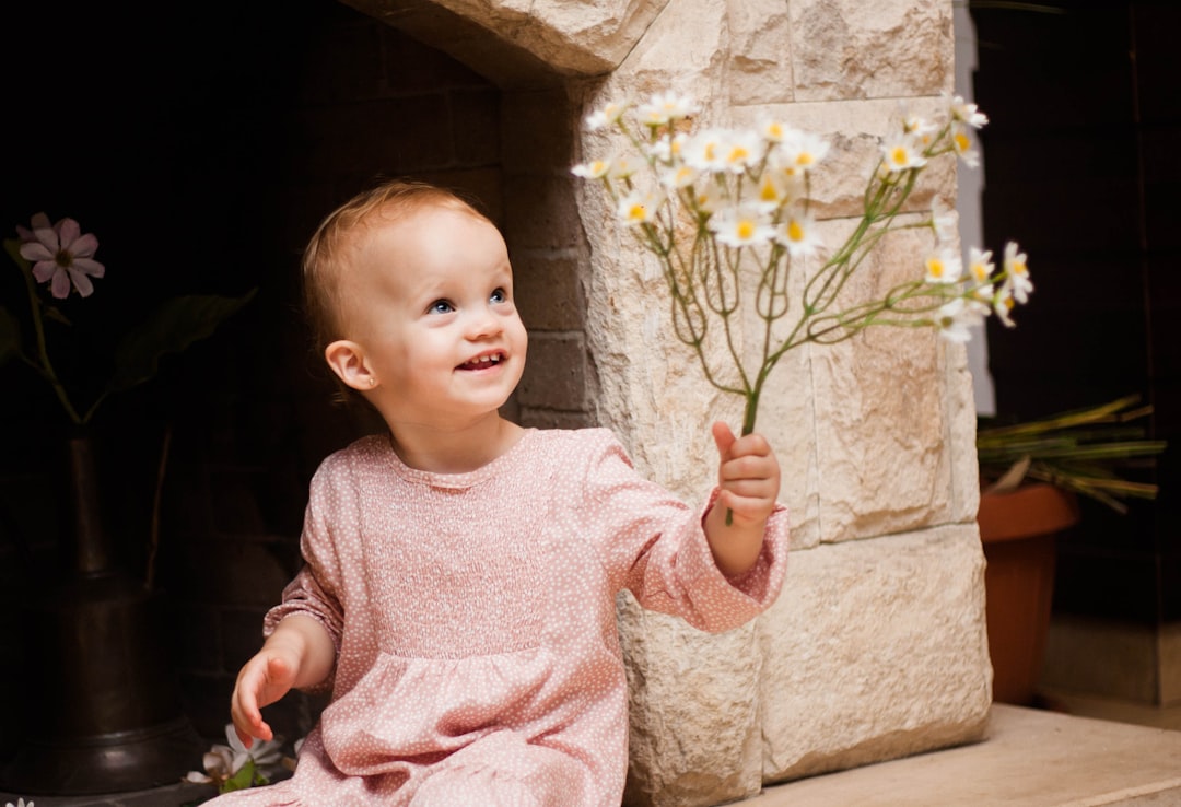 girl in pink sweater holding white and pink floral umbrella