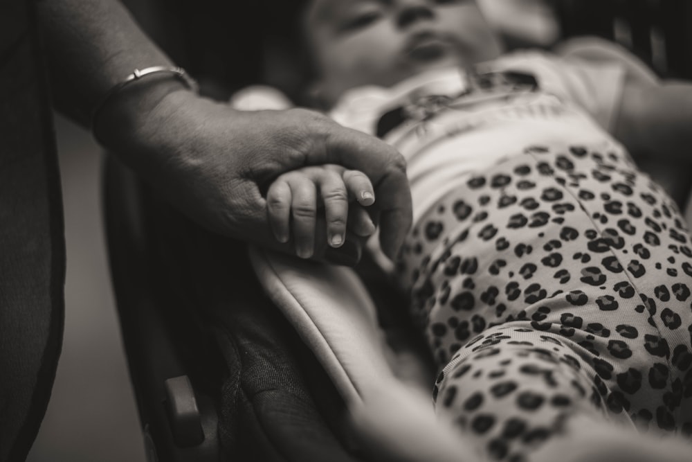 grayscale photo of baby in white onesie