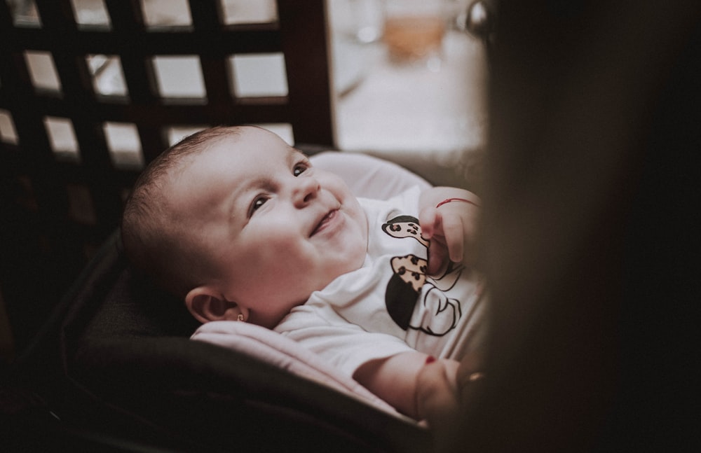 bébé en chemise blanche couché sur le lit