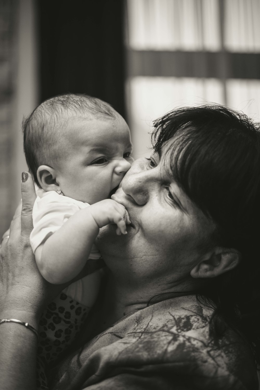 foto em tons de cinza da mulher que beija o bebê