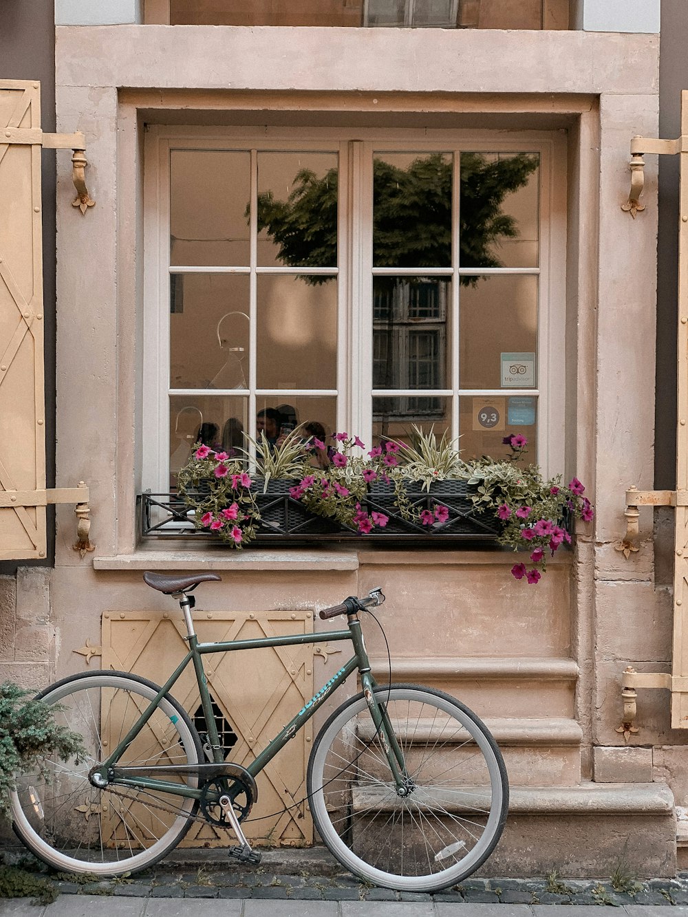 blue city bike parked beside brown wooden window