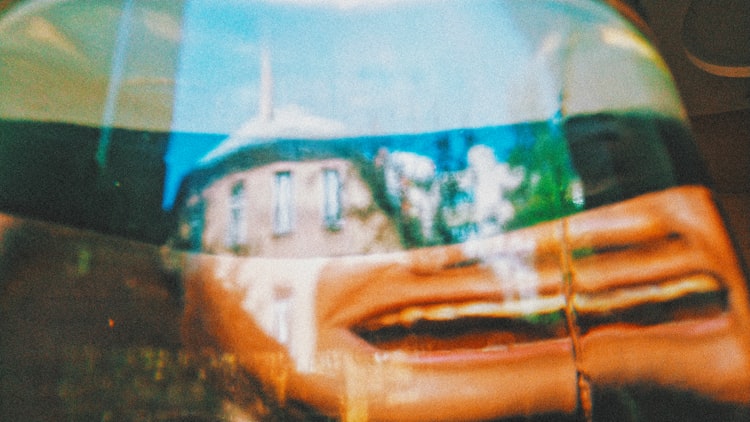 A distorted vintage photograph, with an open mouth mirrored and a house in the distance