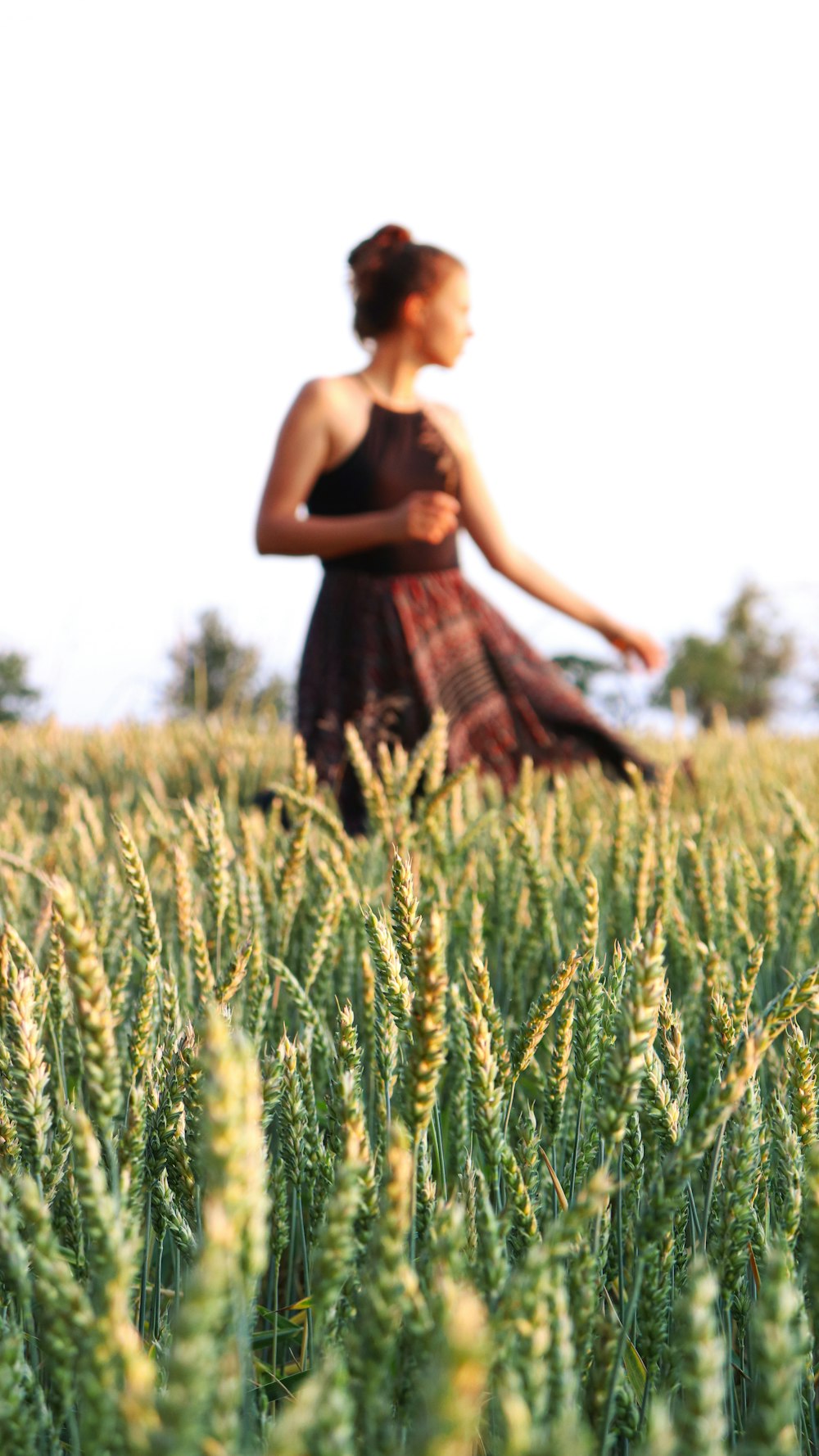 woman in brown and black sleeveless dress standing on green grass field during daytime