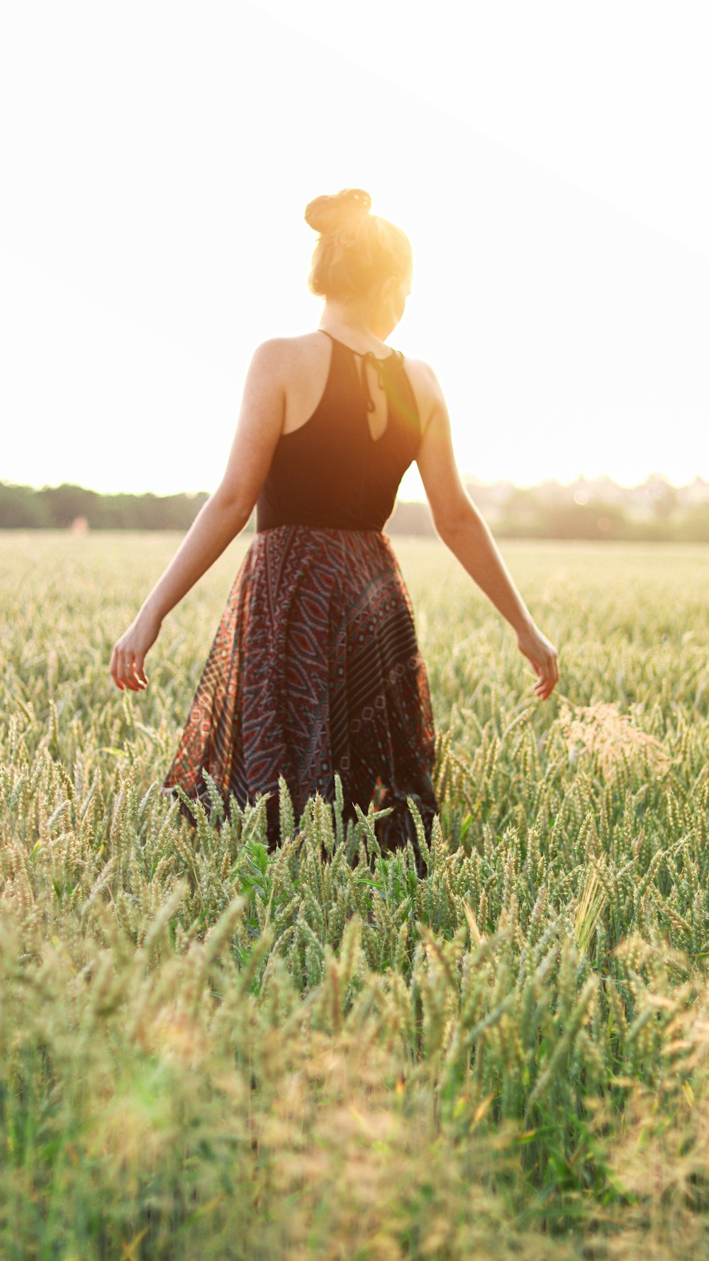 woman in black and brown sleeveless dress standing on green grass field during daytime