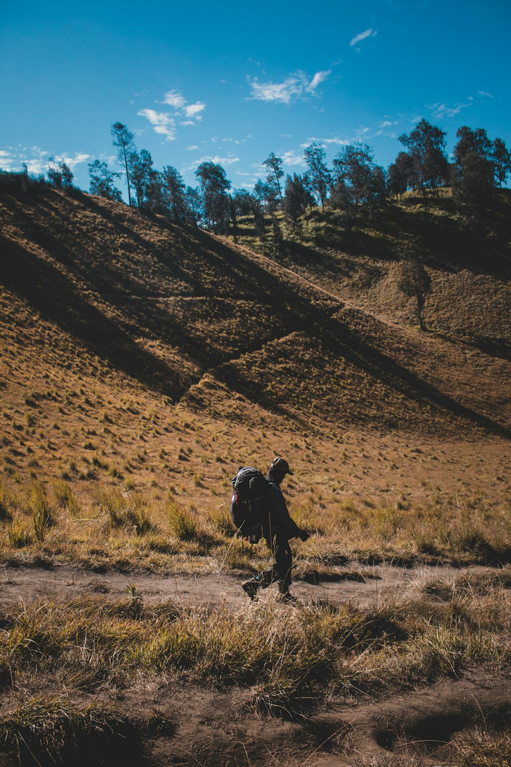 man in black jacket walking on brown field during daytime