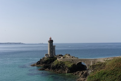 white lighthouse on brown rock formation near sea during daytime