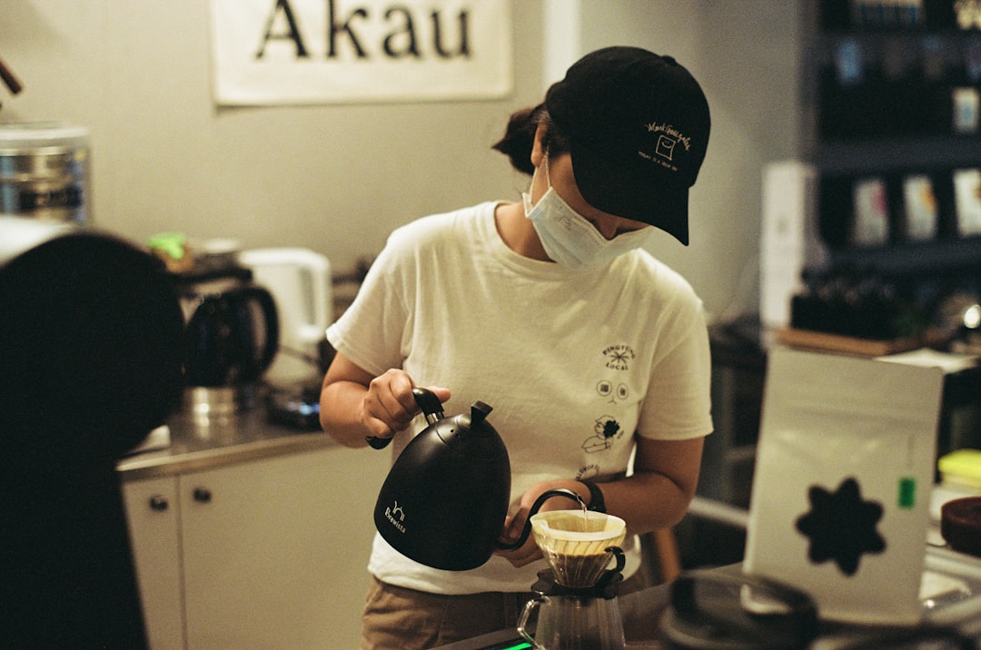 man in white crew neck t-shirt pouring water on clear glass mug