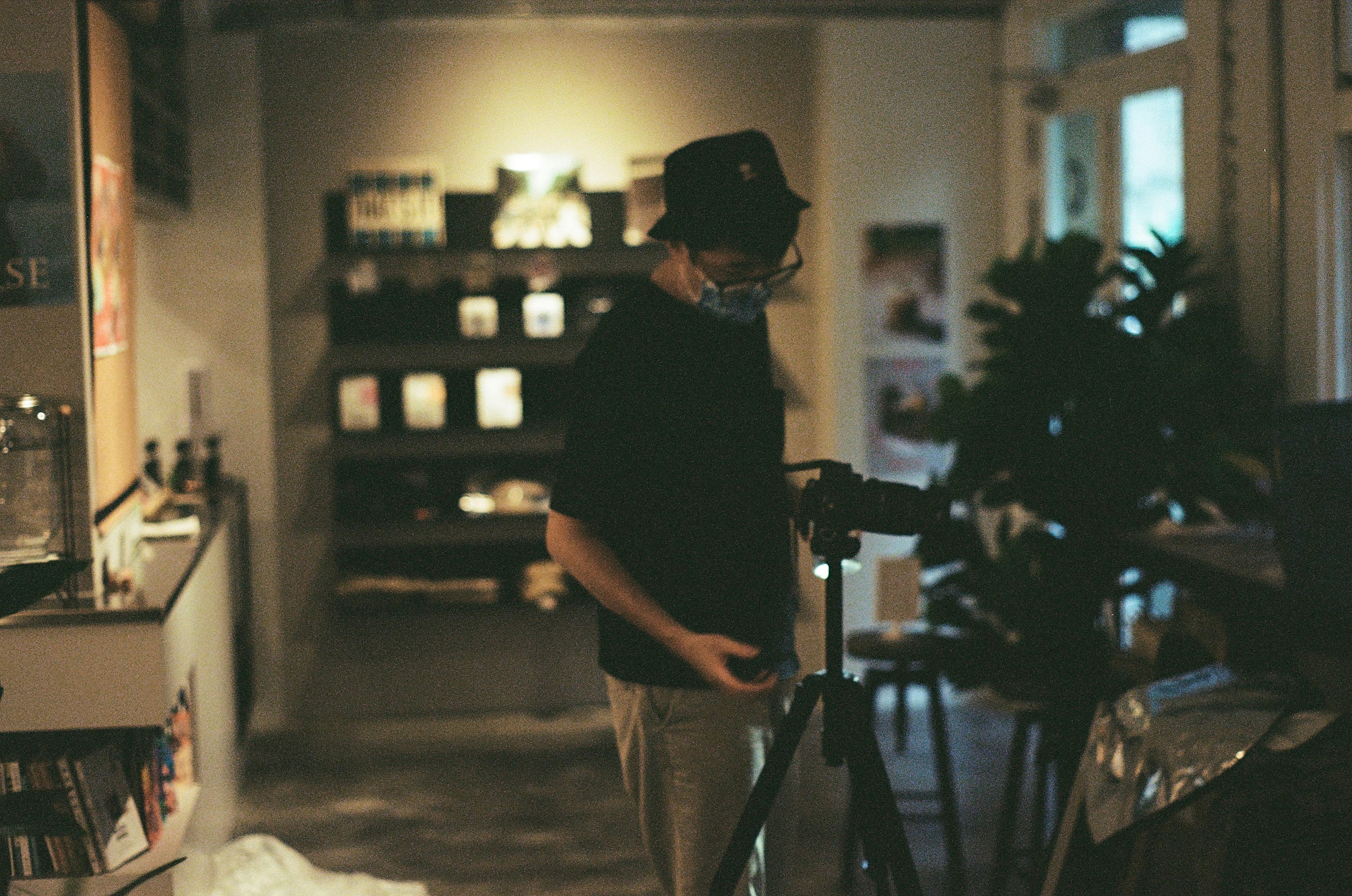 man in black shirt and brown pants standing near black camera tripod