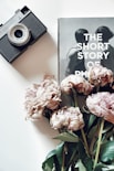 pink roses beside gray and black camera