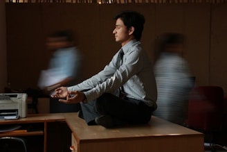 man in white and blue pinstripe dress shirt sitting on brown wooden table