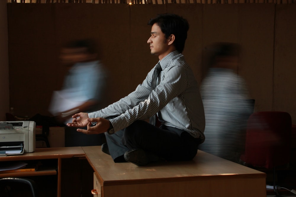 man in white and blue pinstripe dress shirt sitting on brown wooden table