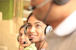 woman in black headphones holding black and silver headphones