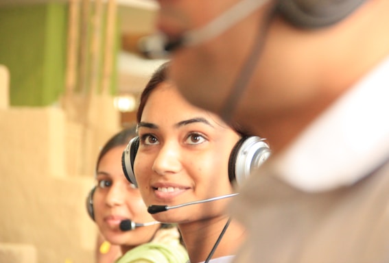 woman in black headphones holding black and silver headphones