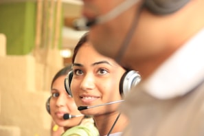 woman in black headphones holding black and silver headphones