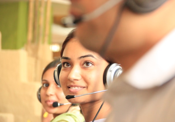 woman in black headphones holding black and silver headphones