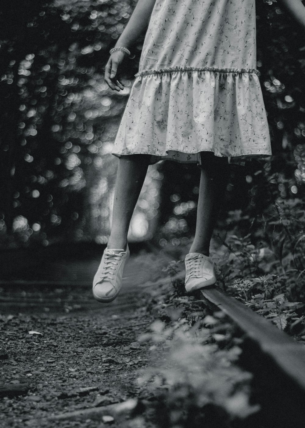 grayscale photo of girl in dress standing on road