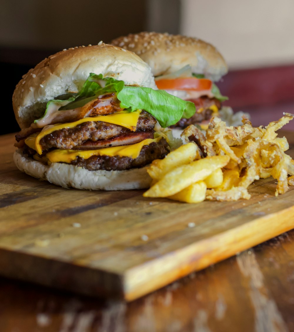 burger with lettuce and fries on brown wooden chopping board