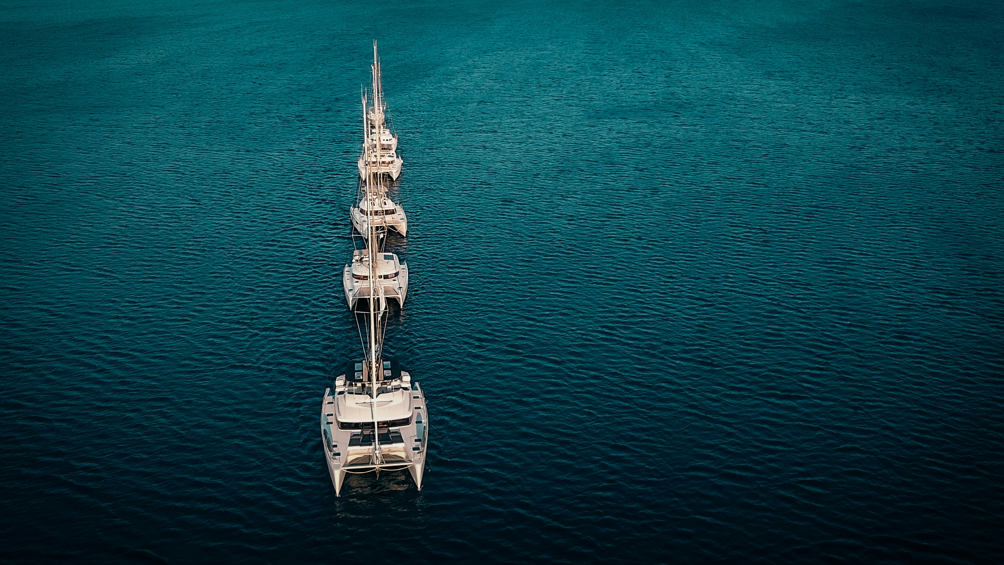 A tall ship sails across a calm blue ocean.