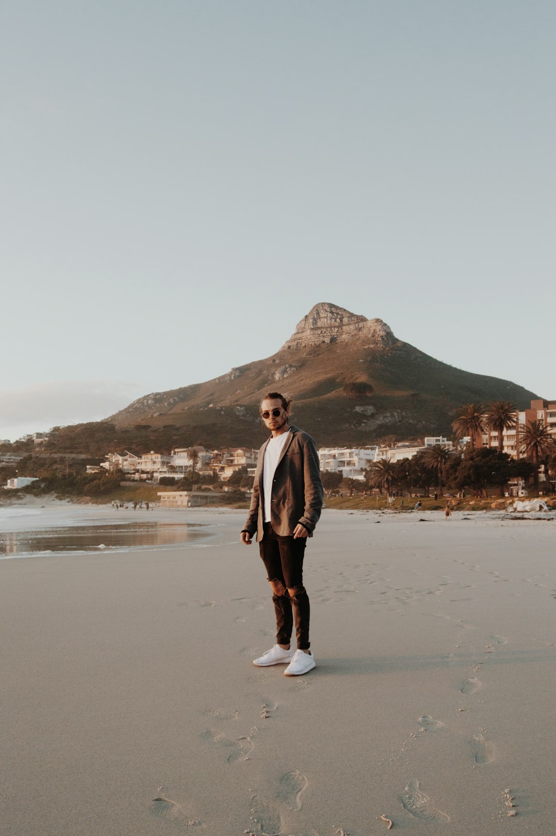 man in white long sleeve shirt and black pants standing on seashore during daytime