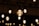 Several decorative light bulbs hanging from the ceiling, emitting a warm glow. The bulbs are evenly spaced and create a pattern of light across a dimly lit background.